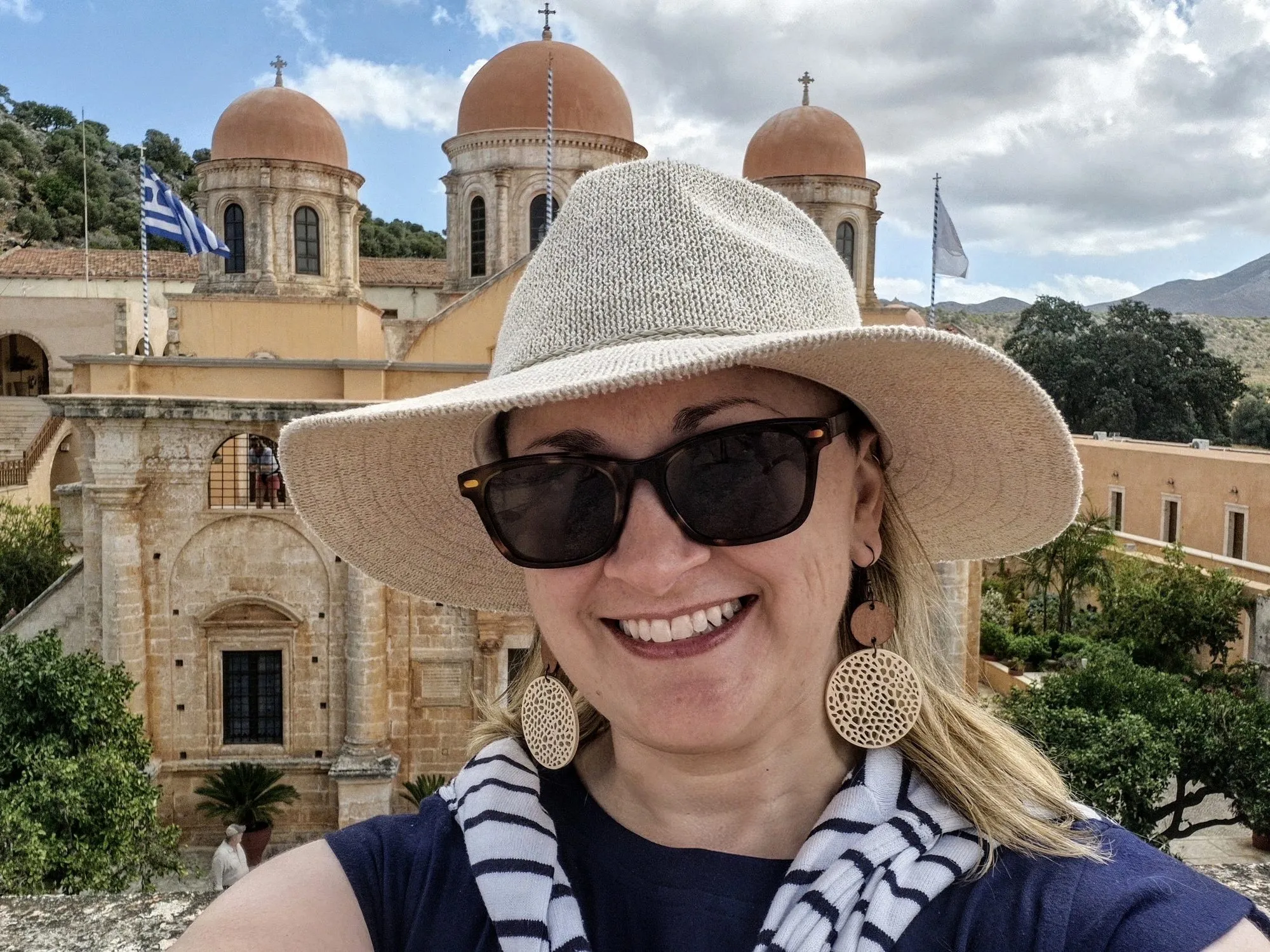 Gayle in a sun hat on a monastery rooftop in Crete, Greece, with domed bell towers behind her